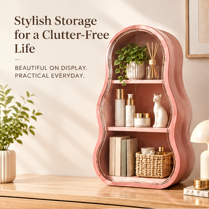 Stylish storage for a clutter-free life — beautiful on display, practical everyday. Pink wave-shaped shelf with clear door styled with plants, skincare and decor objects